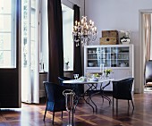Black wicker chairs, chandelier and French windows in elegant dining area