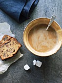 Milchkaffee in rustikaler Tasse und zwei Stücke Dattel-Pecannuss-Kuchen