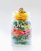 Vegetable salad with peas, avocado, radishes, bread and spinach in a glass jar