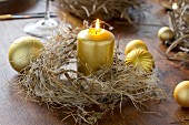 Gold candle in dried wreath on wooden table decorated with Christmas baubles