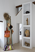 Old shutter used as coat rack next to souvenirs on white shelves