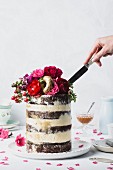 Hochzeitstorte mit frischer Blumendeko, vergoldeten Donuts und Salted Caramel Sauce anschneiden