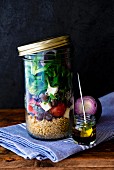 Lunch in a glass jar: quinoa salad, cherry tomatoes, lambs lettuce, black olives and goat's cheese