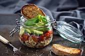 Marinated tofu with sesame seeds, tomatoes, shallots, avocado and toast in a glass jar