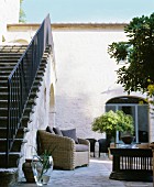 Rattan armchair in traditional Mediterranean courtyard with external staircase to one side