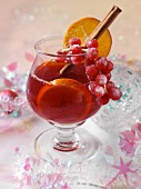 Ein Glas weihnachtlicher Fruchtpunsch mit Orangenscheiben und Zimtstange
