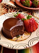 A plate of mexican chocolate creme caramel with strawberries