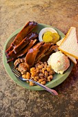 Barbecue ribs with beans, mashed poatoes, white bread, onion and pickle cucumber (Texas, USA)