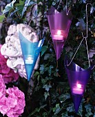 Purple and blue conical tealight holders on ivy-covered garden wall