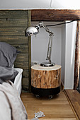 Chrome reading lamp on DIY tree-stump bedside table next to bed