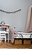 Garland of lettering on grey wall above bed and dolls' house