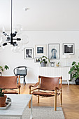 Skandinavische Stühle mit Ledersitzfläche vor der Bilderwand