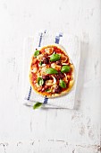 Rustikale Minipizza mit Oliven, Knoblauch, Salami und Basilikum