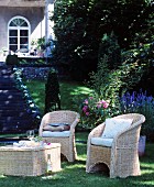 Wicker furniture in shady seating area in classic summer garden