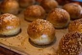 Several sesame seed bread rolls on a wooden board