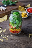 Layered salad with chicken breast, red pepper, sweetcorn, romaine lettuce, tomato and tortilla chips