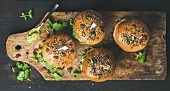 Healthy vegan burger with beetroot and quinoa patty, arugula, avocado sauce, wholegrain bun on rustic wooden board