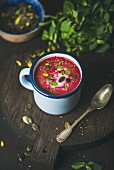 Spring detox beetroot soup with mint, pistachio, chia, flax, pumpkin seeds in blue enamel mug