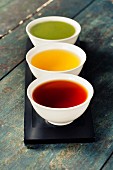 Tea concept. Different kinds of tea (black, green and matcha tea) in ceramic bowls on wooden background