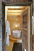 View into wood-clad bathroom through rustic wooden door