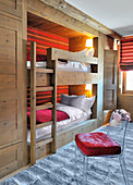 Transparent chair in front of fitted bunk beds with red striped back wall