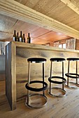 Modern barstool at wooden counter below wood-beamed ceiling