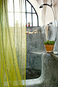 Green curtain in front of masonry shower area with organic shapes