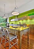 Mirrored table in kitchen with stainless steel cabinets and bright green wall