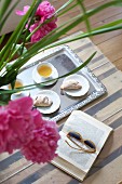 Pastries and tea on tray next to book and pink peonies