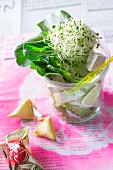 Salad with rice noodles, tofu, peapods, bok choy and shoots in a glass, with a fortune cookie next to it (Asia)