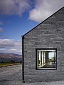 Graue Steinfassade eines modernen Hauses, Blick durchs Fenster