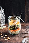 Salad with white cabbage, carrots, green salad, fennel, orange and walnuts in a jar, vegan