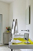 Sink next to vintage ladder and vase of flowers on top of corner cabinet