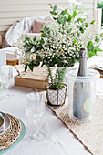 Champagne cooler with champagne bottle and bouquet of flowers on laid table