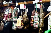 Verschiedene toskanische Salamis hängen in einem Delikatessenladen in Italien