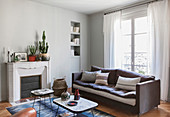 Sofa below window and disused fireplace in living room