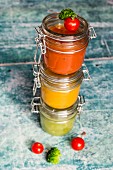 Various colourful soups in glass jars (broccoli soup, tomato soup, pumpkin soup)