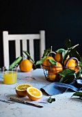 Orangen im Drahtkorb und ein Glas Orangensaft