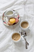 Two cups of coffee with a milk jug and macarons