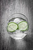 A glass of water with cucumber slices and ice cubes