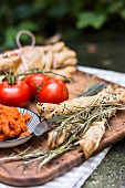 Crispy sesame bread sticks, tomatoes and spread on an outdoor table