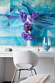 Vertical flower arrangement in front of blue picture on white console table