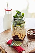 Vegan layered salad with quinoa, chickpeas and avocado in a glass jar