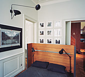 Double bed with reading lamps and wooden headboard in open-plan bedroom