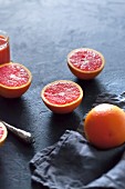 Blood oranges, whole and halved, on a grey concrete surface