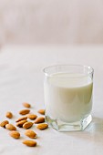 A glass of milk and almonds on a white tablecloth
