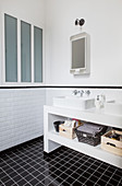 Twin sinks on washstand in black and white bathroom
