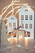 Wooden moose in front of tealights in two house-shaped lanterns