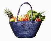 A basket of fresh fruits and vegetables against a white background