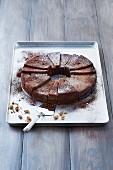 A wreath chocolate cake with nuts on a baking tray
